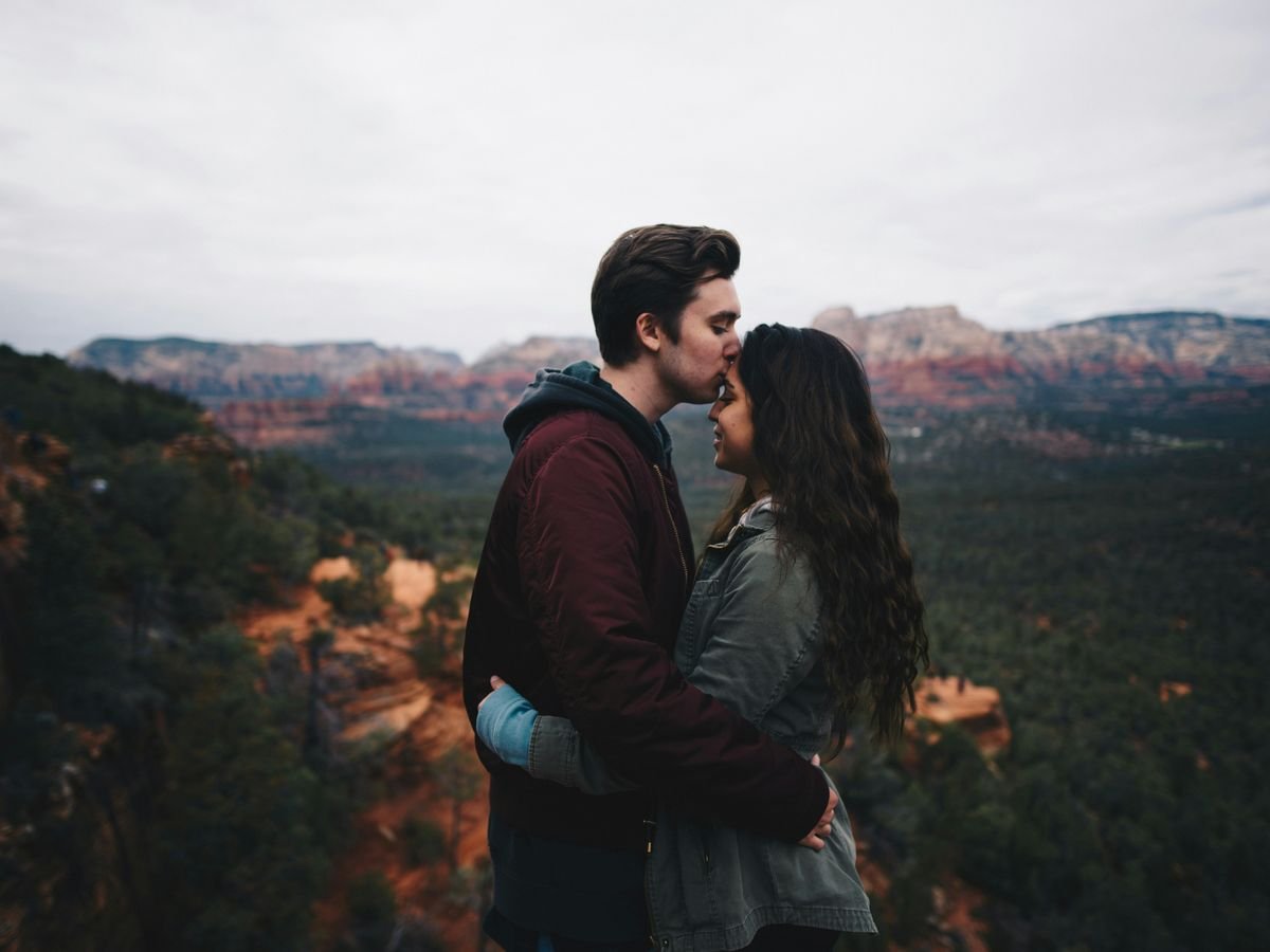 man kissing woman's forehead